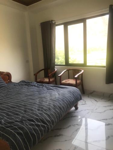 a bedroom with a bed and two chairs and a window at Mai chau Horizon Homestay in Mai Chau