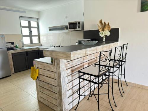 a kitchen with a counter and stools at a bar at Beach front apartment in Grand Gaube