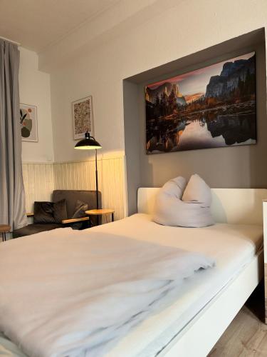 a bedroom with a white bed with a painting on the wall at Einfaches Appartement "Daniel" in Halle in Kröllwitz