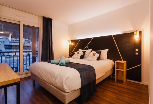 a hotel room with a large bed and a balcony at Garden & City Cauterets Balneo in Cauterets