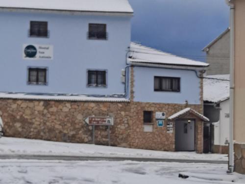 a building with snow on the ground next to a street at HOSTAL SAN ANTONIO in Tragacete
