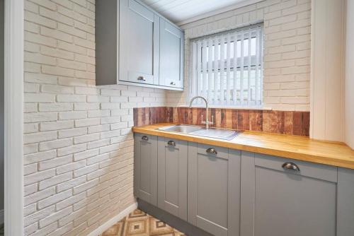 a kitchen with a sink and a brick wall at Pass the Keys Modern home in a seaside town in Seaham