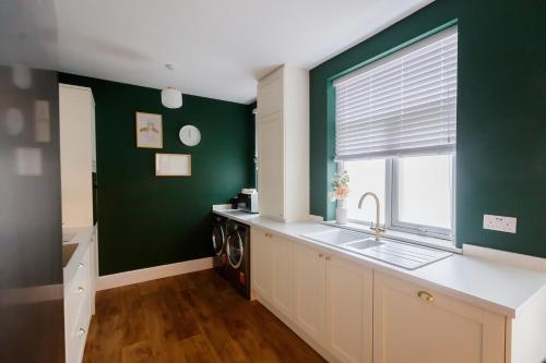 eine Küche mit grünen Wänden, einem Waschbecken und einem Fenster in der Unterkunft The Green House 3 Bed House - Families, Contractors, Free Parking, close to racecourse and city centre in Doncaster