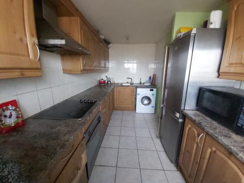 a kitchen with a refrigerator and a washing machine at Essex Riverside in Grays Thurrock