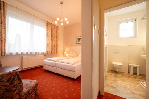 ゼーボーデンにあるPension & Apartments Ertlのベッドとバスルーム付きのホテルルームです。