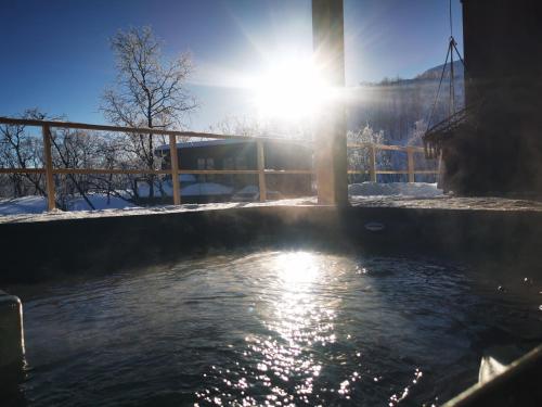 a body of water with the sun shining at Aurora View Lapland, Sky View Bedroom & Jacuzzi in Kilpisjärvi