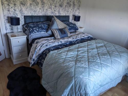 - une chambre avec un lit doté d'une couette et d'oreillers bleus dans l'établissement Cosy cottage Atlantic way, à Carnlough