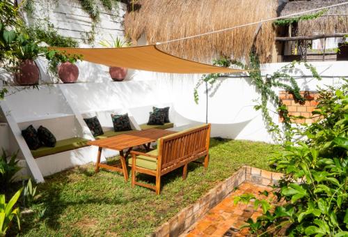 a patio with a wooden table and a bench at Casa do Índico in Praia do Tofo