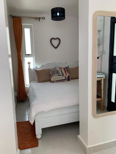 - une chambre avec un lit blanc et un miroir dans l'établissement Dreamy Dwellings Studio Apartment, à Nairobi