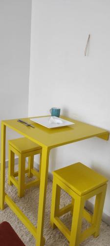 une table jaune avec deux tabourets dans une pièce dans l'établissement Dreamy Dwellings Studio Apartment, à Nairobi