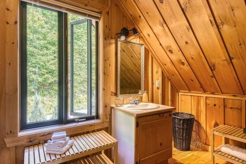 a bathroom with a sink and a mirror in a cabin at Luxurious log cabin with private spa in Lac-Superieur