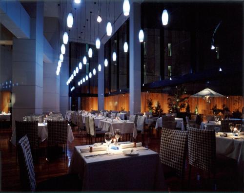 un restaurante con mesas blancas, sillas y luces en Hotel Molino Shin Yuri, en Kawasaki