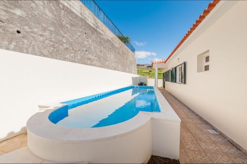 a swimming pool in the side of a white building at Casa Eleanor by LovelyStay in Calheta