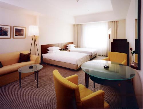 a hotel room with two beds and a couch at Hotel Molino Shin Yuri in Kawasaki