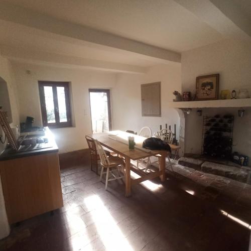 une cuisine avec une table et des chaises ainsi qu'une cheminée dans l'établissement maison typique cévenole avec jardin, à Mialet