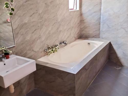 uma casa de banho com uma banheira branca e um lavatório. em RPC Blissful Homes & Hotel em Kuala Lumpur