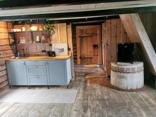 a kitchen in a log cabin with a sink and a television at Stabburet på Balsnes Gård in Hitra
