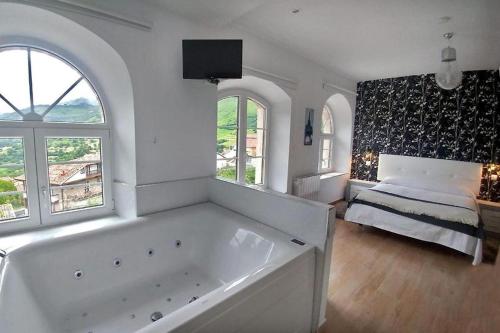 een grote witte badkamer met een bad en een bed bij Alojamiento rural El Refugio in Tudanca