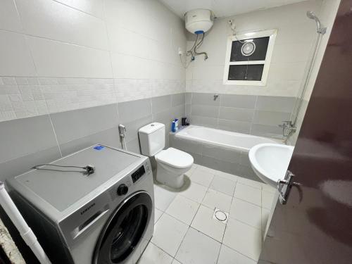 a bathroom with a washing machine and a toilet at Sam Home in Sharjah
