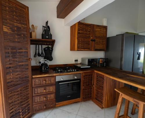 托佛海灘的住宿－Casa do Índico，厨房配有木制橱柜和炉灶烤箱。