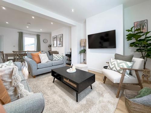 a living room with a couch and a table at Salters Cottage - Stunning Modernised 3 BR Home Just Steps From the Beach in Budleigh Salterton