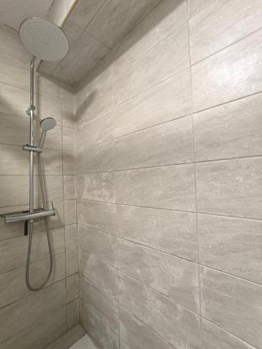 La salle de bains est pourvue d'une douche et d'un grand mur en carrelage. dans l'établissement Appartement de vacances - Splendide vue sur mer, Parking privé, au Barcarès