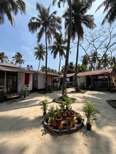 a building with palm trees and plants in a courtyard at LAKSHDEEP COTTAGES in Canacona