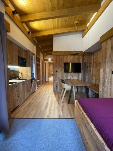a kitchen with wooden cabinets and a table with a purple bed at Penzion Brnenka in Špindlerův Mlýn