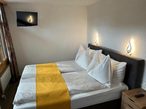 a bed in a room with two lights on the wall at Post Hotel Vista in Zweisimmen