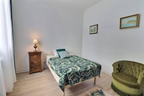 una camera da letto con un letto e una sedia verde di La Dolce Vita, jolie maison familiale a Troyes