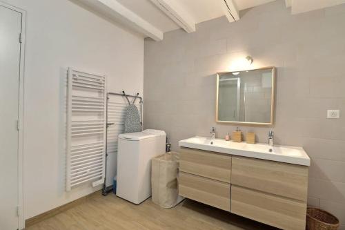 uma casa de banho branca com um lavatório e um espelho em La Dolce Vita, jolie maison familiale em Troyes