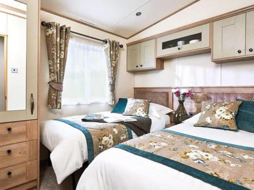 1 dormitorio con 2 camas y ventana en Unwind@13 Badger Lakes, Haggerston, Northumberland en Beal