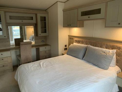 a bedroom with a large white bed and a desk at Unwind@13 Badger Lakes, Haggerston, Northumberland in Beal