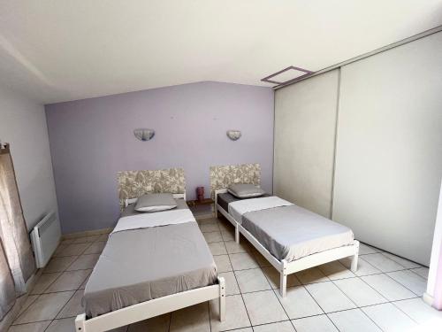 2 bedden in een kamer met paarse muren bij Charme et Confort in Villeneuve-lès-Béziers