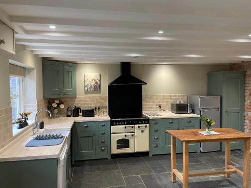 a kitchen with green cabinets and a stove top oven at The Cider House at Stathe Farm in Burrowbridge