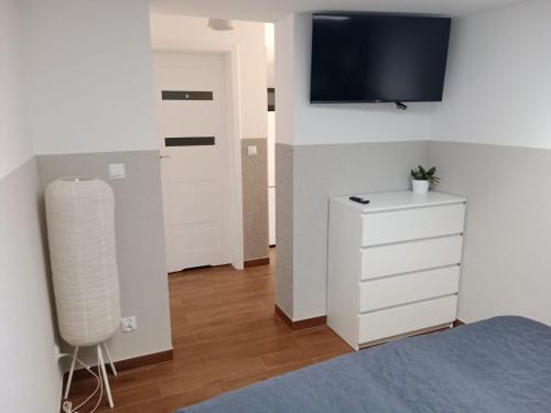 a bedroom with a white dresser and a tv on a wall at Gościnne mieszkania M1 in Białystok