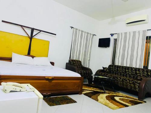 Habitación de hotel con cama y sofá en AULNES RESIDENCE HOTEL, en Cotonou