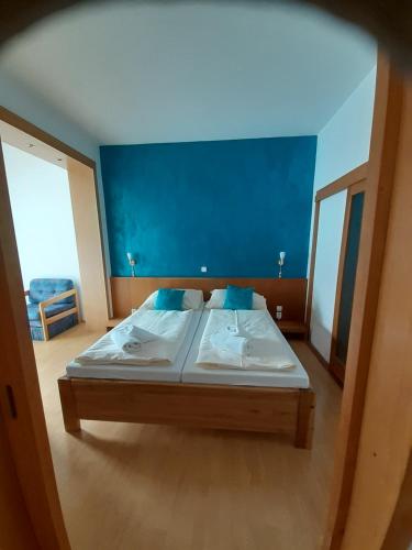 - une chambre avec un grand lit et un mur bleu dans l'établissement Hotel Gold, à Terchová