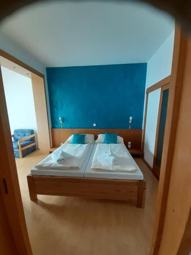 a bedroom with a large bed with a blue wall at Hotel Gold in Terchová