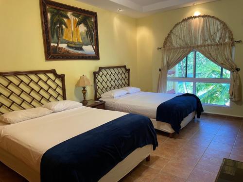 1 dormitorio con 2 camas y ventana en Honduras Shores Plantations, en Tela