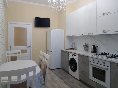 uma cozinha com um frigorífico branco e uma mesa e uma mesa e cadeiras em Lux Apart em Chisinau