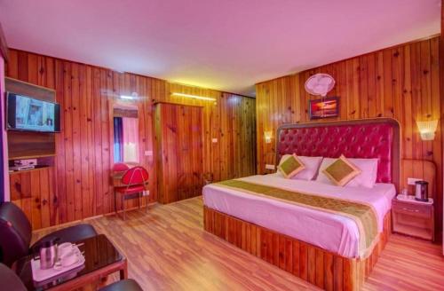 a bedroom with a large bed in a room with wooden walls at sky hill house in Manāli