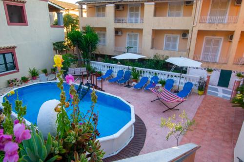 un cortile con piscina, sedie e ombrelloni di Almyra Apartments & Studios ad Agios Gordios