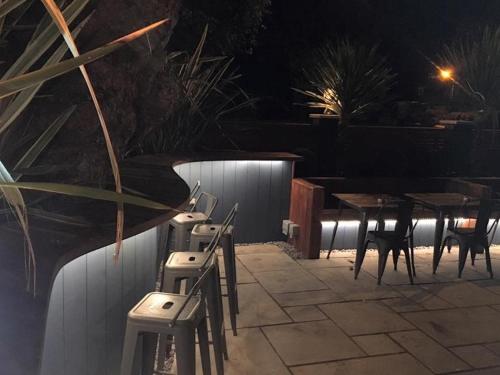 grupa krzeseł i stołów na patio w nocy w obiekcie Oxgang Kitchen Bar & Rooms w mieście Grangemouth