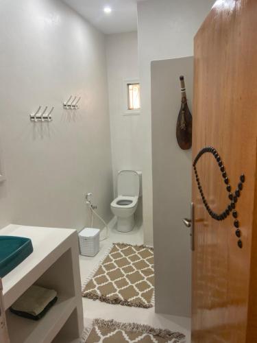 a bathroom with a toilet and a sink and a door at RESIDENCE DAR YASMINa in Mezraya