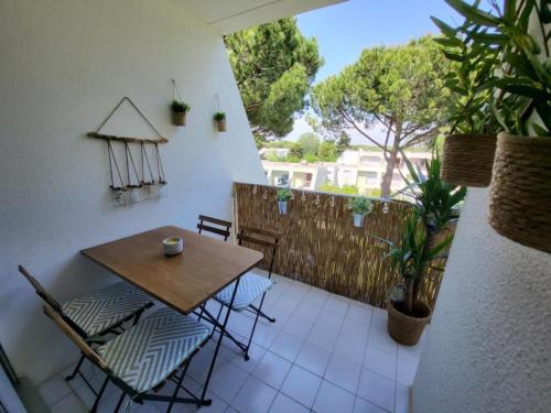 eine Terrasse mit einem Holztisch und Stühlen auf dem Balkon in der Unterkunft L Or des sables, la Petite Motte, residence avec piscine in La Grande-Motte