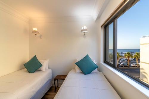 two beds in a room with a view of the ocean at Beachfront Seaview in Cape Town