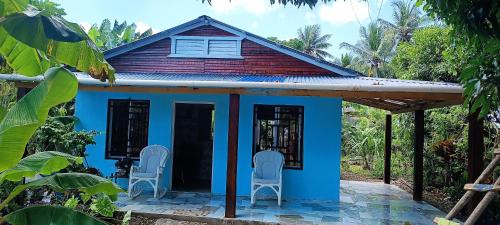 a blue house with two chairs in front of it at Casa de campo in San Felipe de Puerto Plata
