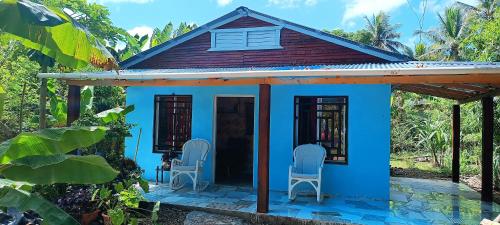 una piccola casa blu con due sedie davanti di Casa de campo a San Felipe de Puerto Plata