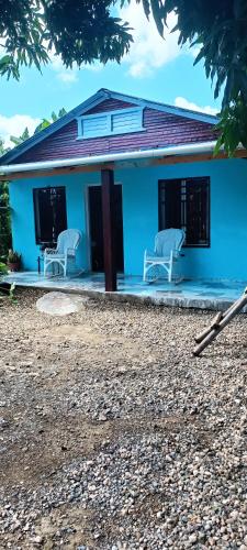 a blue house with two white chairs in front of it at Casa de campo in San Felipe de Puerto Plata